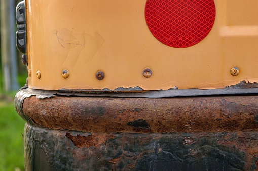 Weathered and rusted back bumper of a school bus.