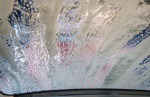 Soap streaks on car windshield in automated car wash.