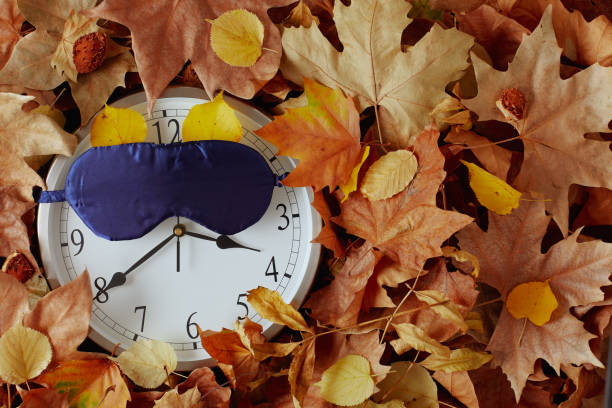 istock autumn background with clock, sleeping mask and leaves 1502433419