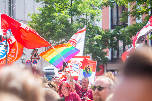 Munich, Germany, 24 June 2023: Gay Pride celebration in Munich, people waving Bayern Munich and rainbow flags together
