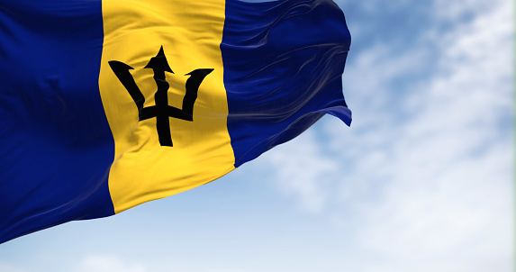 Barbados national flag waving on a clear day. Blue and yellow flag with a black Triton in the center. 3d illustration render. Fluttering fabric