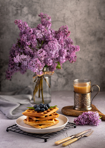 Food photography of waffles, bouquet of lilacs, tea