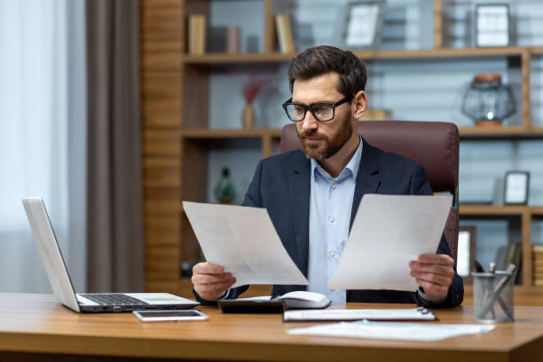 istock Serious and focused financier accountant on paper work inside office, mature man using calculator and laptop for calculating reports and summarizing accounts, businessman at work 1502450008