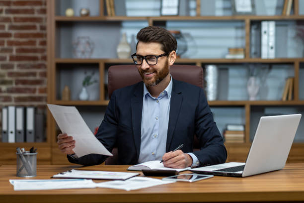 istock Mature successful financier working inside office at workplace with contracts and papers businessman behind paper work reading financial report experienced analyst satisfied with achievement results 1502450055
