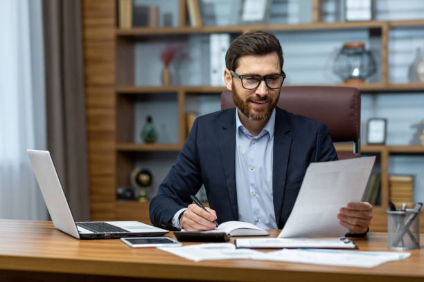 istock Mature successful financier working inside office at workplace with contracts and papers businessman behind paper work reading financial report experienced analyst satisfied with achievement results 1502450369