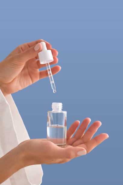 istock Serum with a pipette in female hands on a blue background. 1502454983