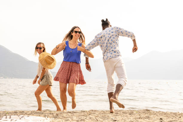istock Three adults dancing on the beach by the lake at sunset 1502461978