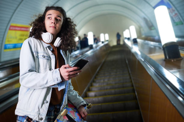 istock Teenage skateboarder with smartphone standing on moving escalator 1502462049