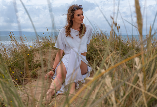A youngf woman in a sand dune on a beach in Devon, UK