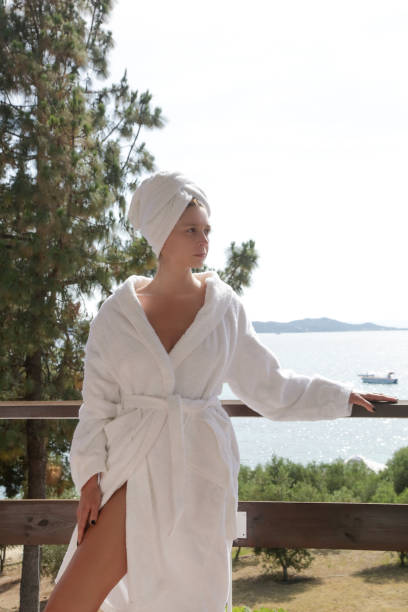 istock Woman in white terrycloth bathrobe on balcony. 1502464379