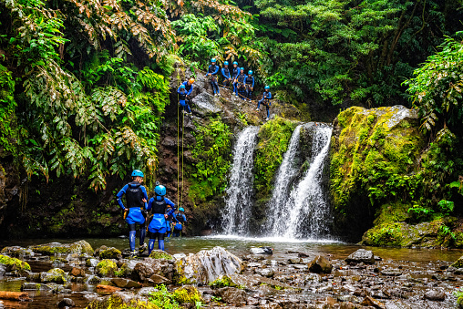 Achada, Portugal - July 5th, 2022: People practicing canyoning near a waterfall in the Natural Park of Ribeira dos Caldeiroes in Azores, Sao Miguel Island. Travel adventure