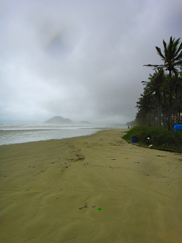 Strip of wet sand on the beach of Riviera de Sao Lourenco, during the ebb tide on a rainy day and undertow at sea. - BERTIOGA,  SAO PAULO,  BRAZIL.