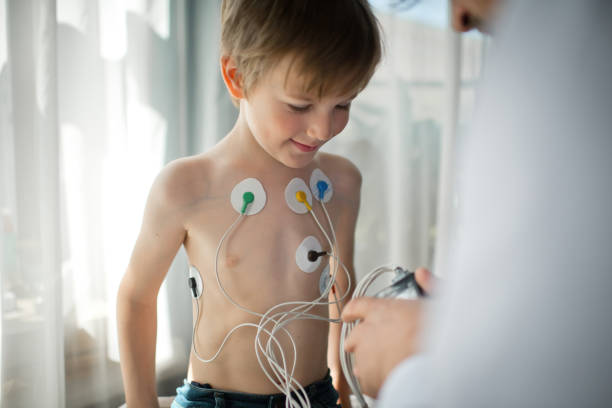 Doctor adjusting  ECG holter monitor for a child to check his heart health stock photo