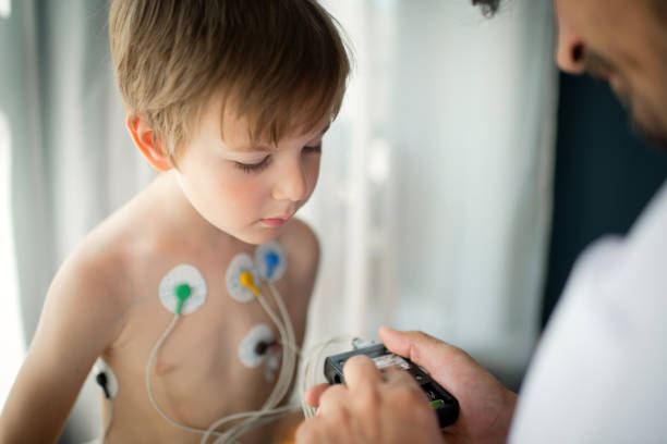 médico ajustando monitor holter de ecg para que un niño revise la salud de su corazón - pulse trace electrode human heart holter fotografías e imágenes de stock