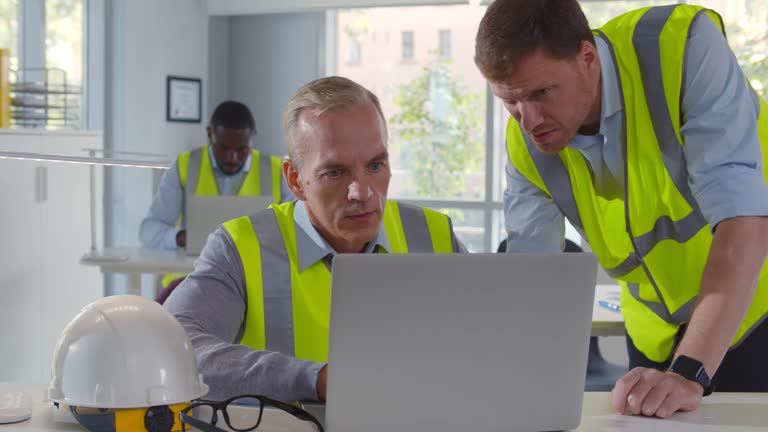 Two male architects working on laptop in office