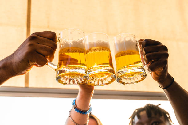small group of young adult multiethnic friends toasting with three mugs of beer stock photo