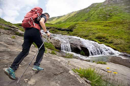 A hiker taking a photo of one of the waterfalls of Cento Fonti, at Cesacastina, in the Gran Sasso Monti della Laga National Park, in Abruzzo, Italy