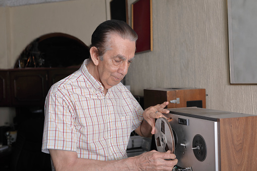 Senior man holding a reel to reel audio tape.