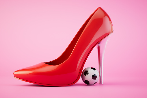 Playing women's football. A red heeled shoe and a soccer ball on a pastel background. 3D render.