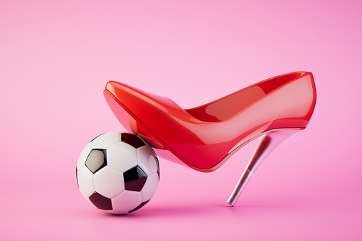 The concept of women's football. A red heeled shoe steps on a soccer ball. 3D render.