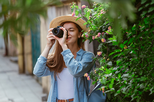 Photographer traveler in hat takes pictures of sights while walking along the street of a european city. Vacation and traveling lifestyle