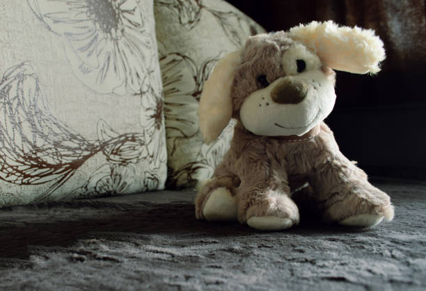 Cute plush dog toy sits on velour sofa in close-up