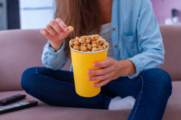 istock Woman resting on the couch and eating crispy caramel popcorn while watching TV 1502523369