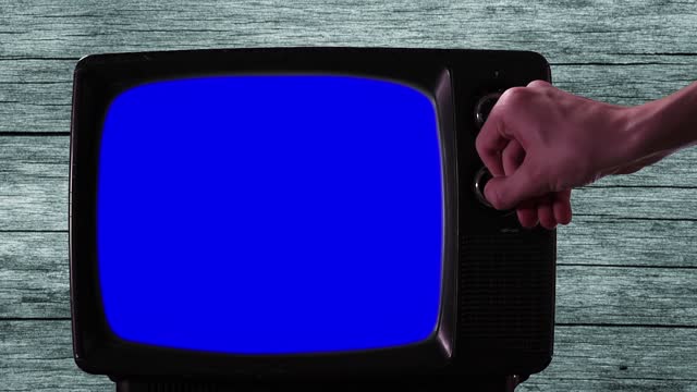 Man Hand Turning On Old TV with Blue Screen. Close-Up. 4K Resolution.