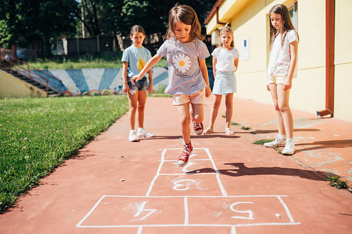 Cheerful children playing hopscotch in the schoolyard