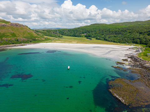 This aerial drone photo shows Calgary Bay on the Isle of Mull in Scotland. It is a beautiful beach with white sand and turquoise water.