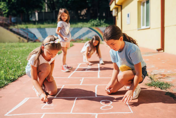 istock Playful children drawing hopscotch with chalks in the yard 1502528019