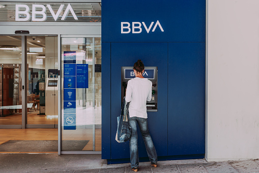 Segovia, Spain - June 16, 2023: The woman withdraws money from the ATM of the bank BBVA
