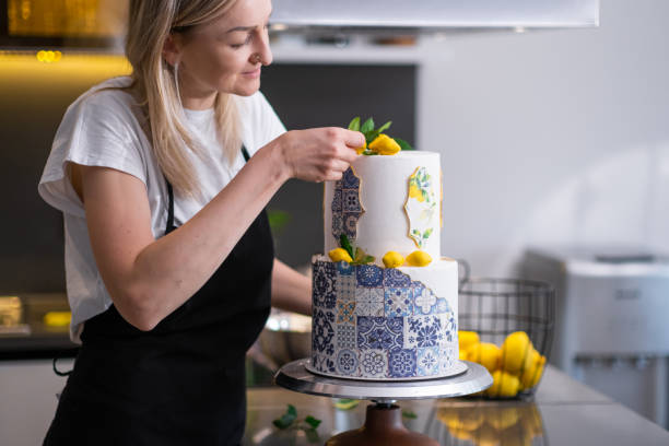 istock Satisfied confectioner in apron decorating two-tiered cake with patterns and yellow lemons 1502534502