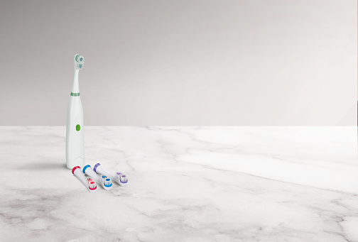Electric toothbrush set with replacement brushes on a marble surface