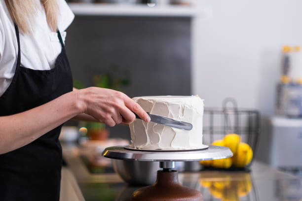 istock Professional confectioner spreading white sugar free mastic around baked cake with knife 1502535458