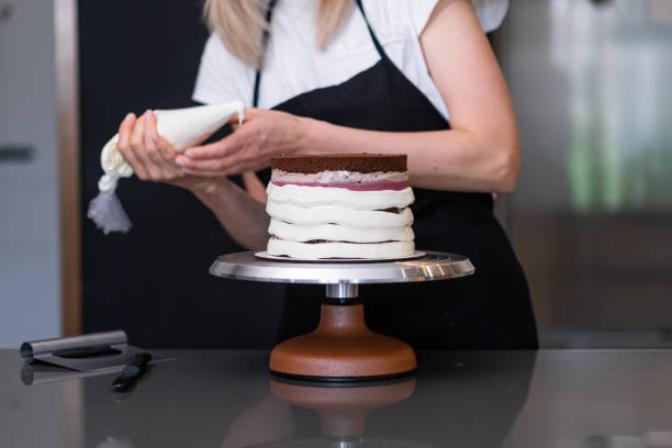 istock Skilled woman putting sweet white mastic around baked cake using pastry cone 1502535642