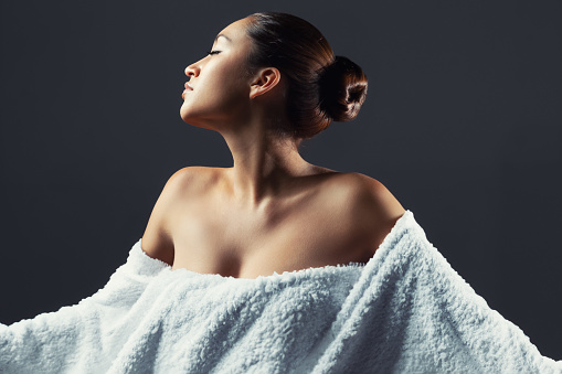 Portrait of an attractive young Hispanic woman wrapped in a large white bath towel