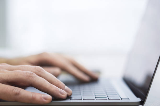 istock The image presents a man's hands up close as they navigate a modern laptop's keyboard, against a blurred office scene 1502537405