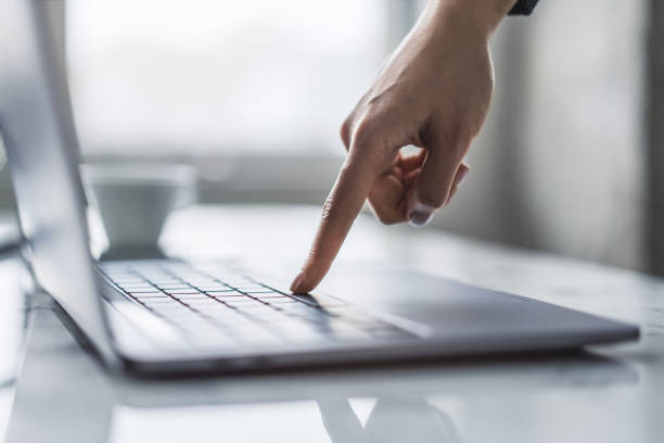 Against a blurred office scene, the image details a woman's hands nimbly typing on a trendy laptop keyboard Against a blurred office scene, the image details a woman's hands nimbly typing on a trendy laptop keyboard nimbly stock pictures, royalty-free photos & images