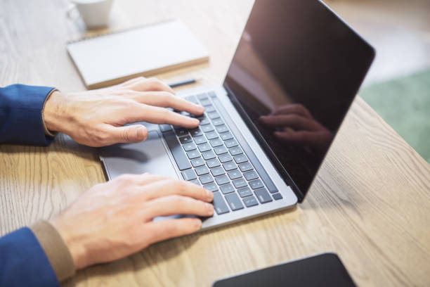 istock A man's hands are seen up close, typing on a contemporary laptop, with a softly blurred office scene in the background 1502537549