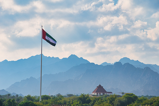 Scenic landscape of Hatta mountains with a tall pole with United Arab Emirates flag above the city in the territory of Dubai emirate of United Arab Emirates
