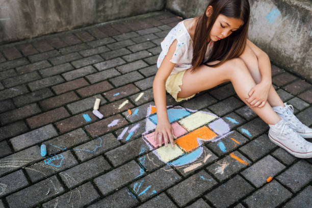istock Girl sitting on the ground and drawing colorful hearth shape with chalks 1502545269