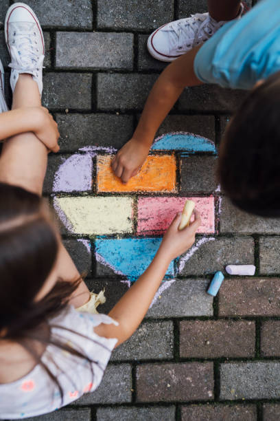 istock Children sitting on the ground and drawing colorful hearth shape with  chalks 1502545372