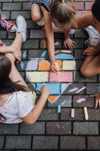 istock Children sitting on the ground and drawing colorful hearth shape with  chalks 1502545703