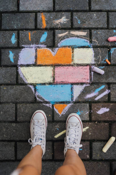 istock Child standing next to a chalk drawing heart shape on the ground . 1502545823