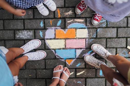 Above shot of Children standing next to a children’s chalk drawing heart shape on the ground .Love and unity concept