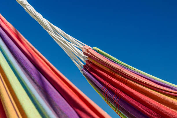 Close-up image of two rainbow-colored hammocks against the blue sky