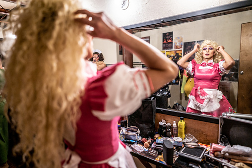Drag queen getting dressed backstage before performance at theater
