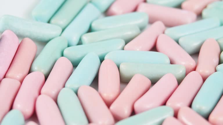 Multicolor Chewing Candies Rolls on White Background From Left to Right in Slow Motion. Bright Tasty Colourful Texture Of Blue and Pink Sweets in Motion