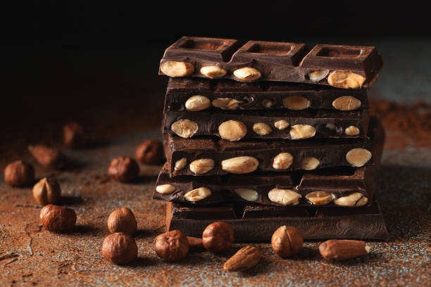 istock Dark and milk chocolate with nuts on a dark background sprinkled with cocoa powder. 1502558949
